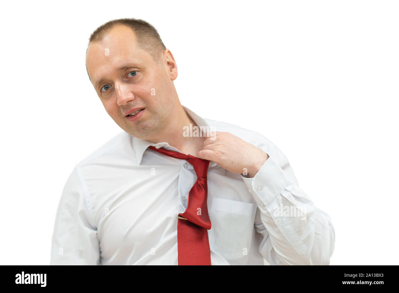 portrait of tired businessman taking off his tie. Isolated on white. man in shirt taking off his red necktie while standing against white background. Stock Photo