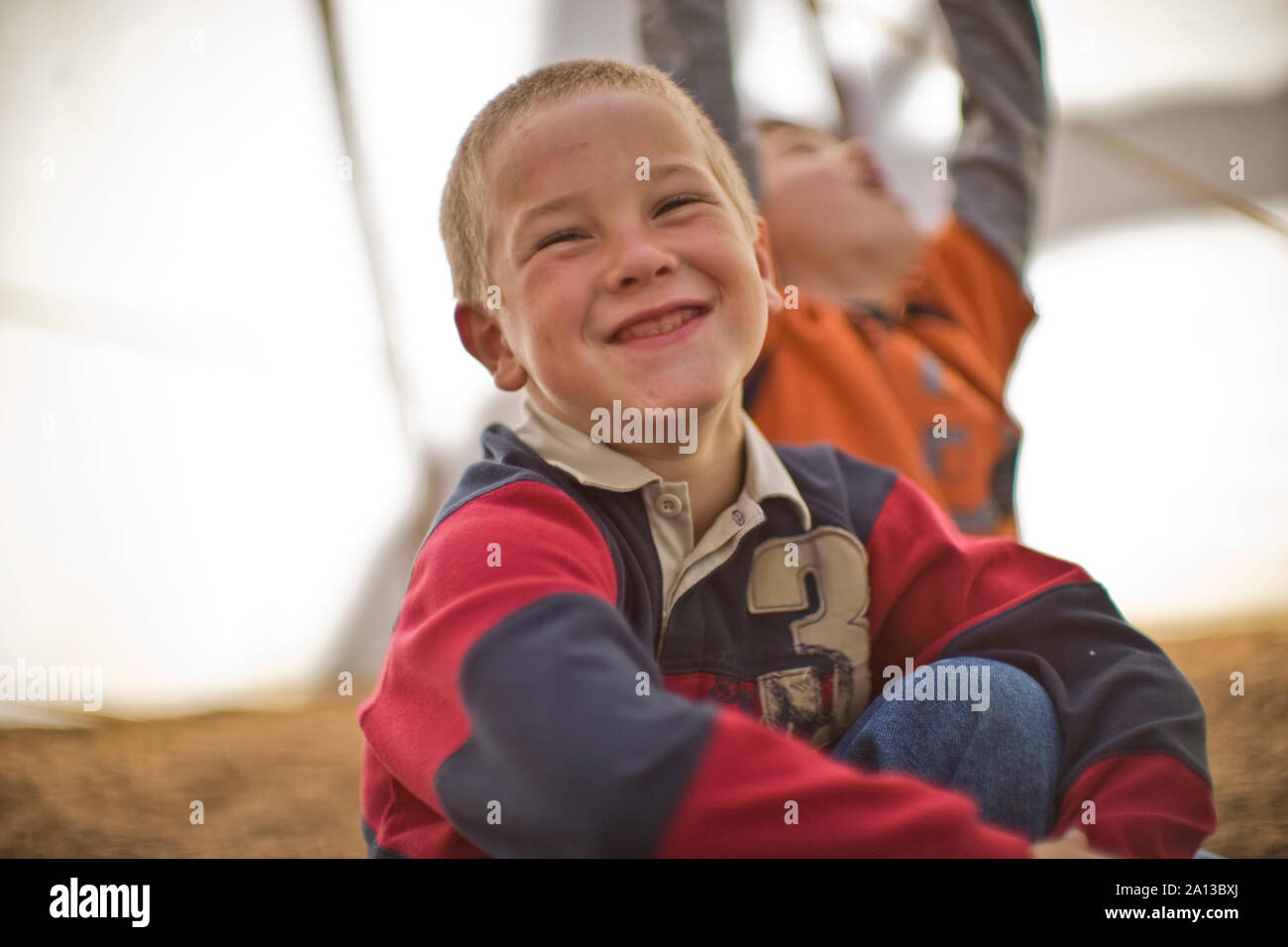 Smiling young boy sitting in a playground Stock Photo - Alamy