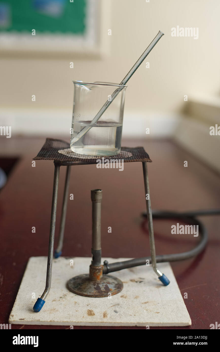 Heating water in a beaker with a gas burner in a school science lab. Laboratory with students