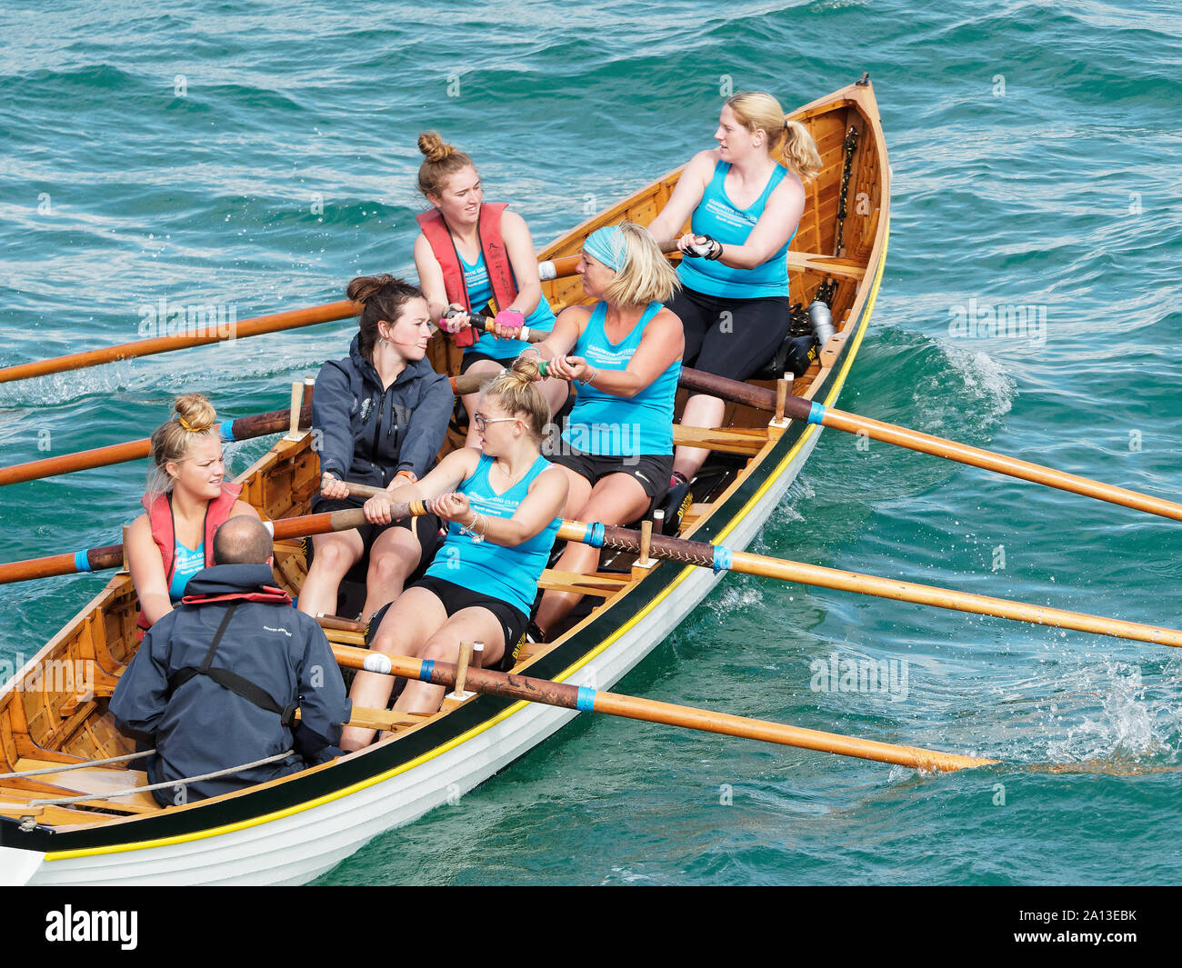 Women rowing in teams of six in traditional hand built pilot gig boats. the annual west country