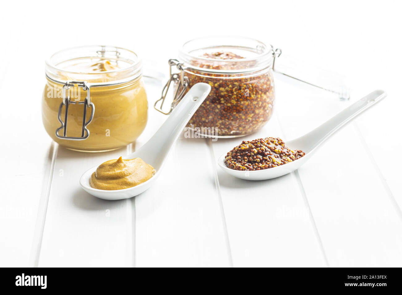 Yellow mustard and whole grain mustard in ceramic spoon Stock Photo Alamy