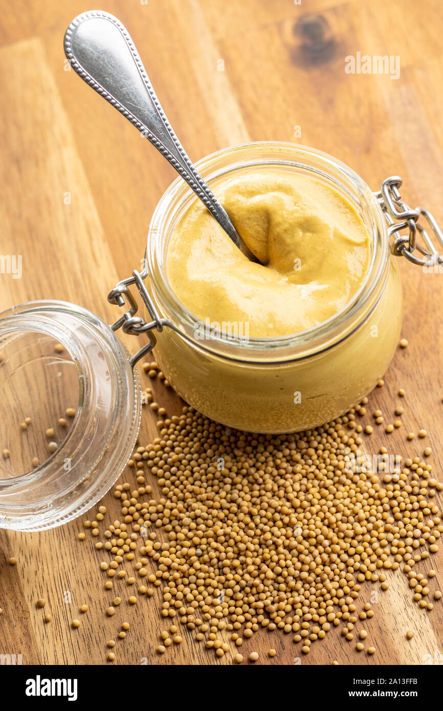 The yellow mustard in jar on wooden table. Stock Photo
