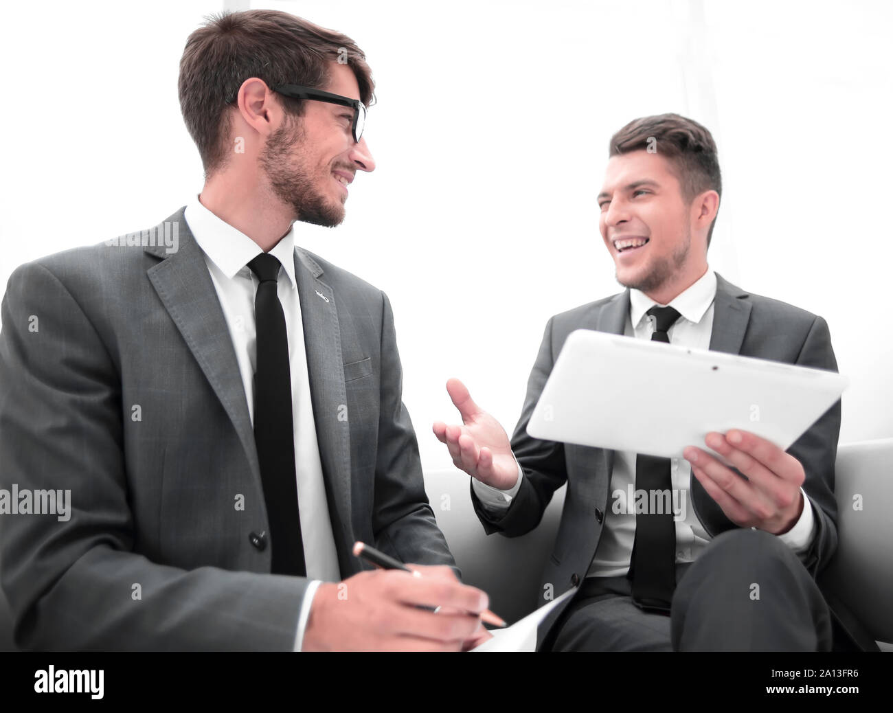 two men chatting while sitting in the office Stock Photo