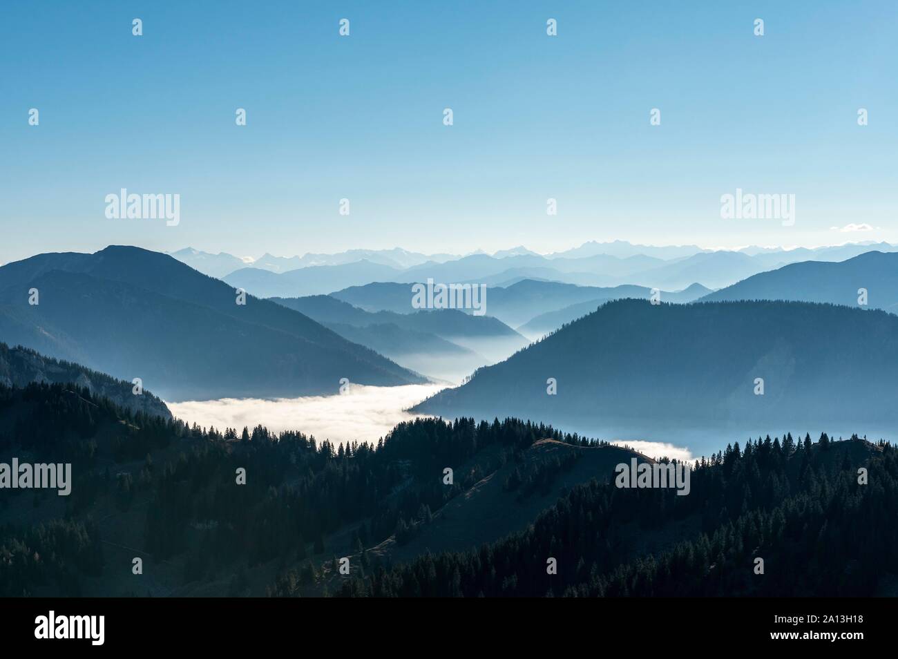 Mountain chains one behind the other in back light, view of alpine panorama from the summit of Breitenstein, high fog over the valley, Fischbachau Stock Photo