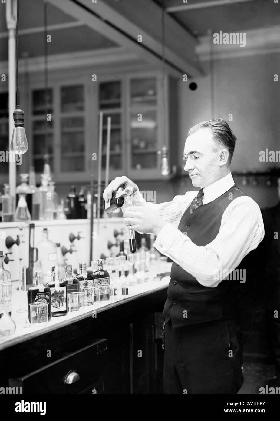 Chemist G. F. Beyer testing a bottle of bootleg liquor during the prohibition era. Stock Photo