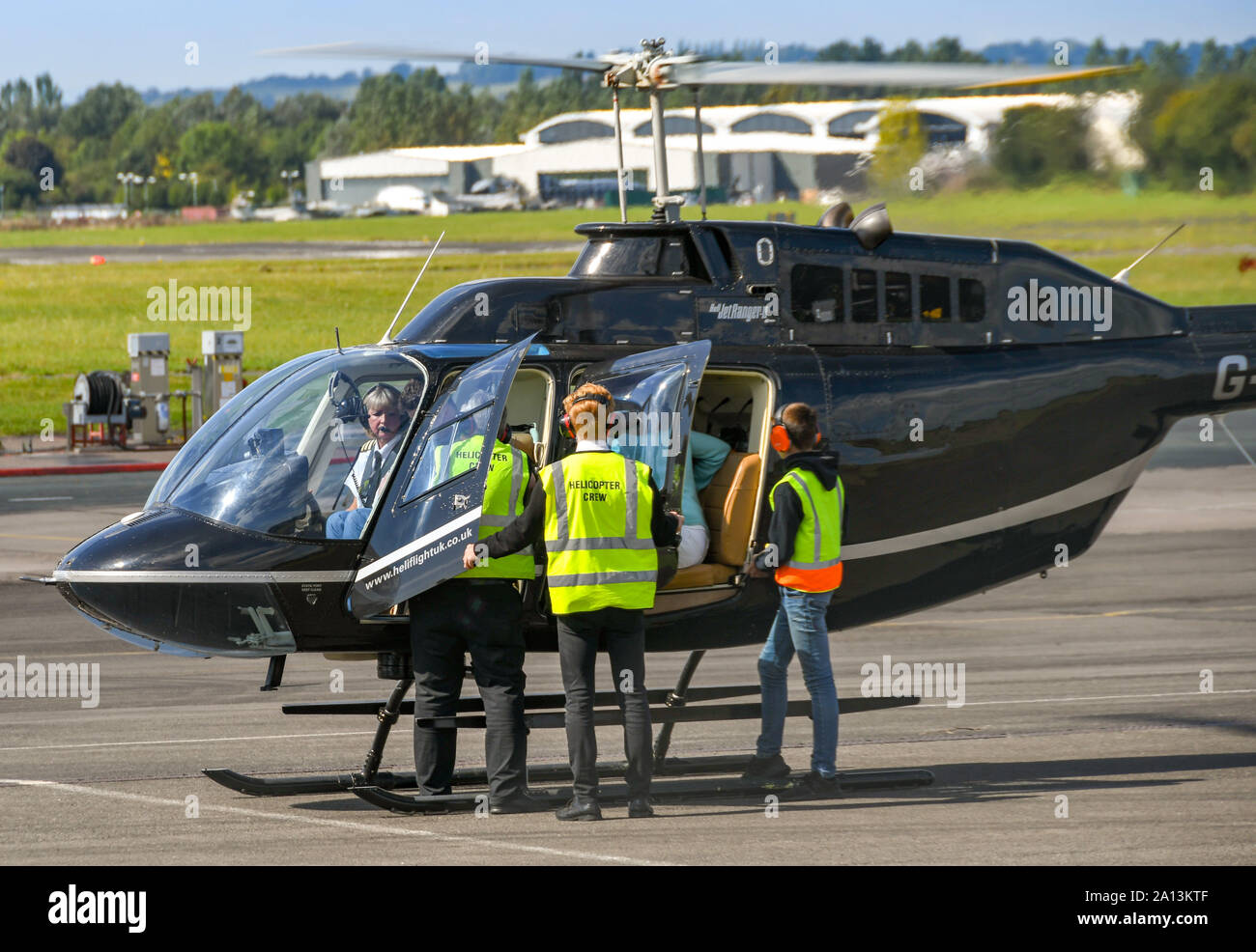 GLOUCESTER, ENGLAND - SEPTEMBER 2019: Helicopter crew seeing passengers into a helicopter before a pleasure flight from Gloucester Staverton Airport. Stock Photo