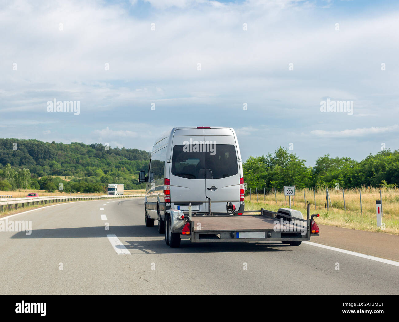 White minibus with empty tow truck transporter on highway. Space for text Stock Photo