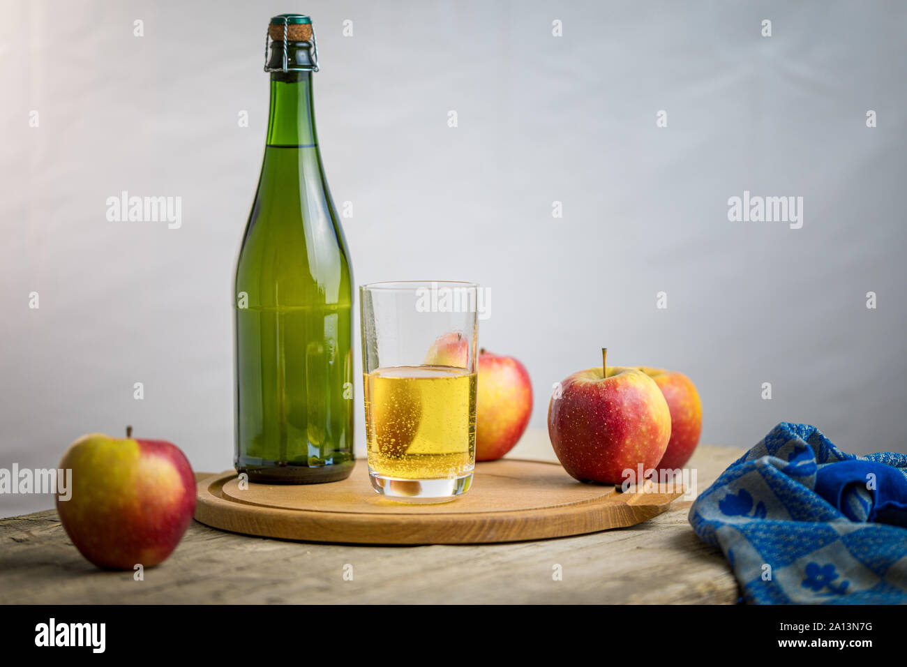 Apple cider in a glas with contextual elements, bottle, apples, tea