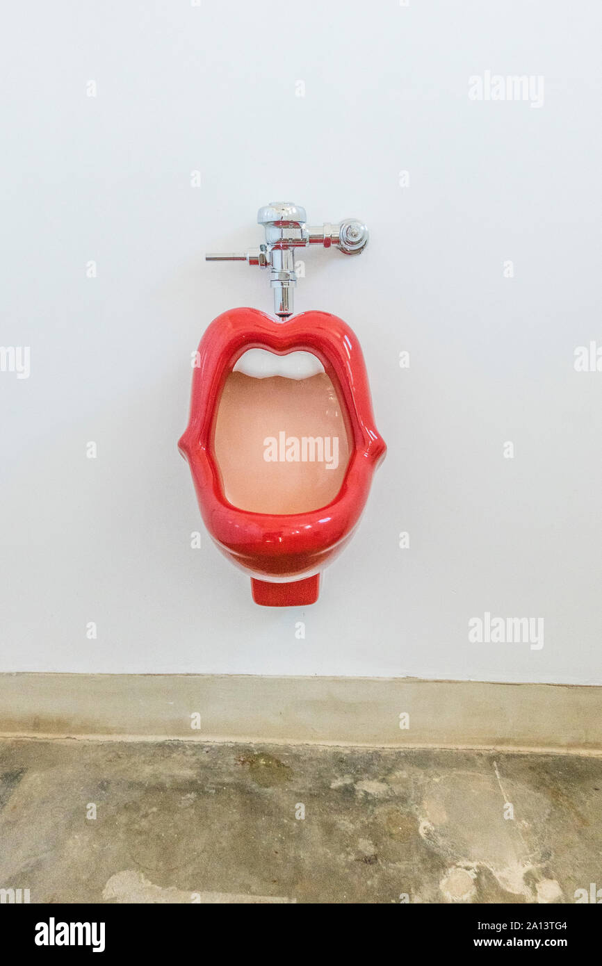 A red lips urinal with white teeth in the men's bathroom at the