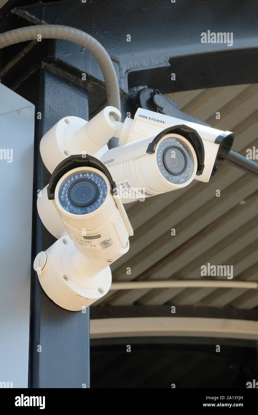 Three outdoor security surveillance cameras mounted together and viewing in separate directions for small airport security monitoring. Stock Photo