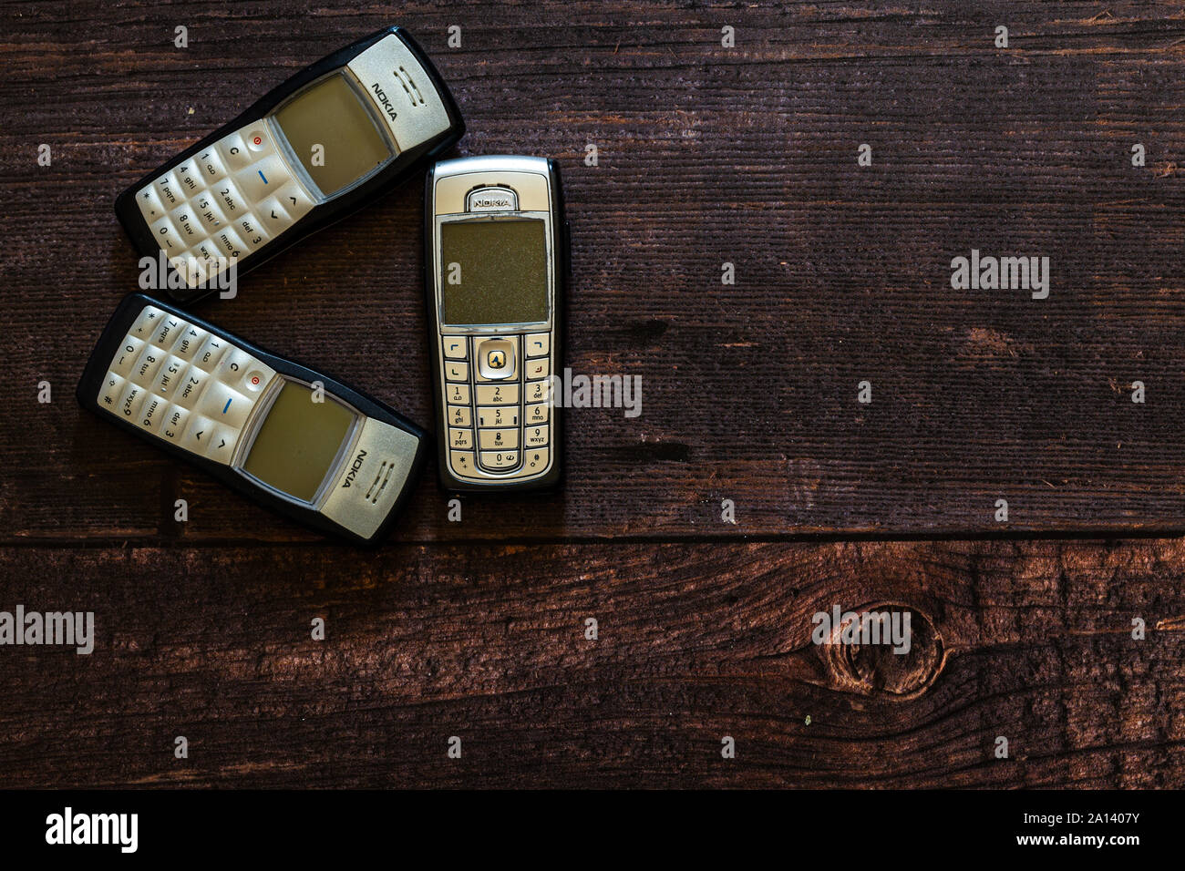 Old Nokia mobile phone laying on brown wooden floorboards. there is copy space on the right of the image. Stock Photo