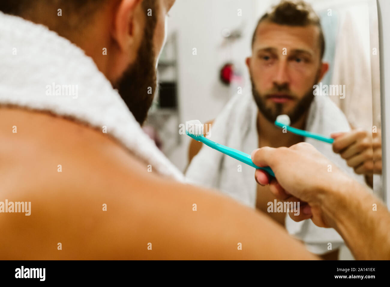 Man with toothbrush cleaning teeth at bathroom Stock Photo