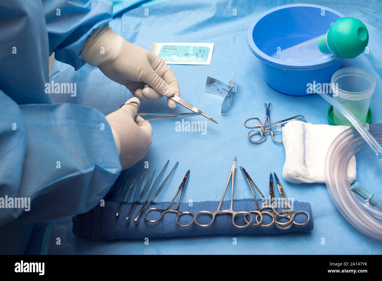 Surgical technician loads scalpel with surgical blade on sterile table. Stock Photo
