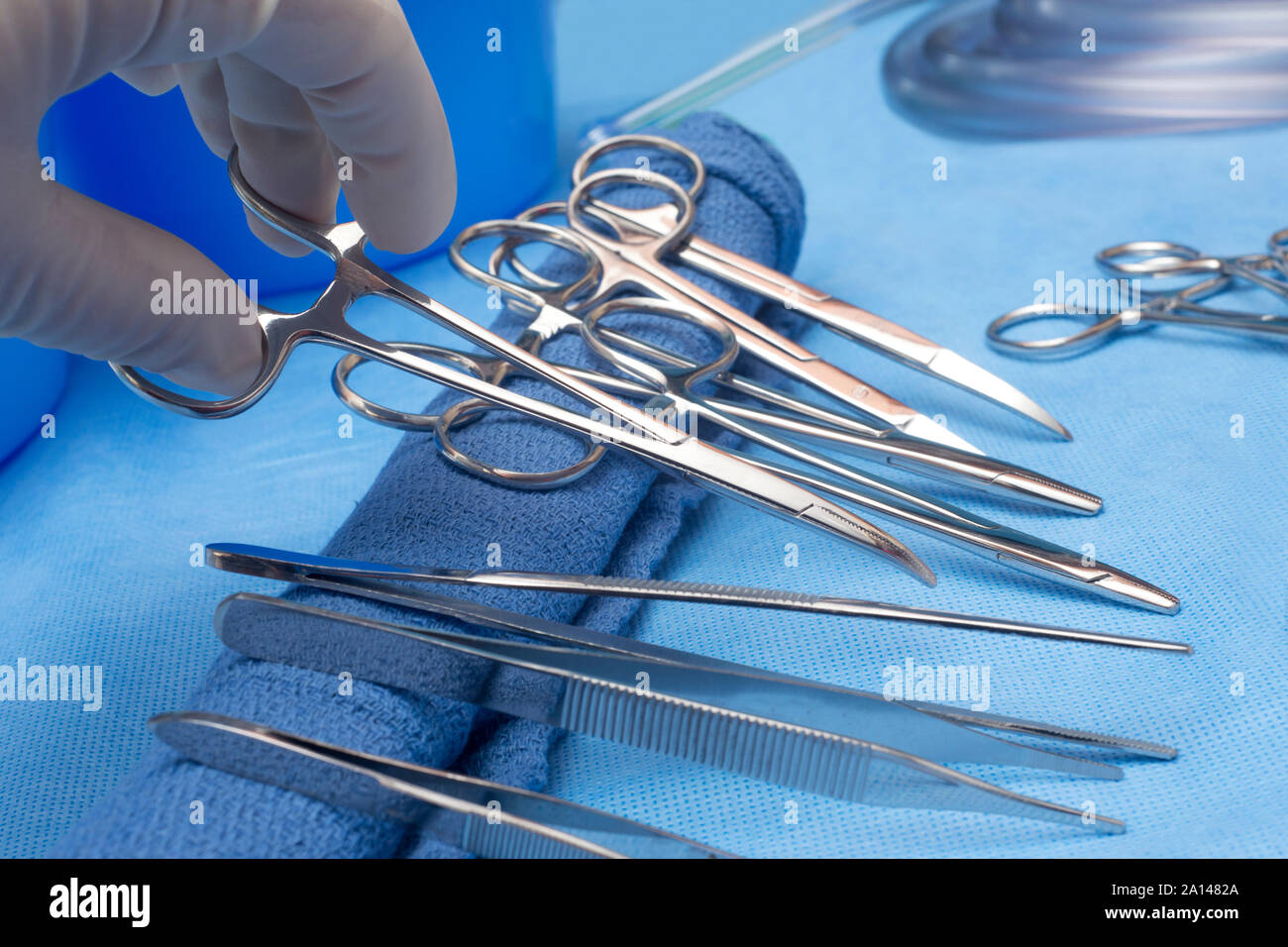 Surgeon selects curved hemostats from sterile table. Stock Photo