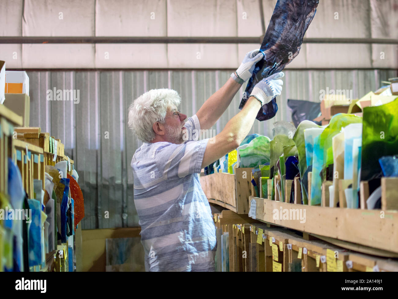 A glass artist wears gloves to protect his hands, and examines the
