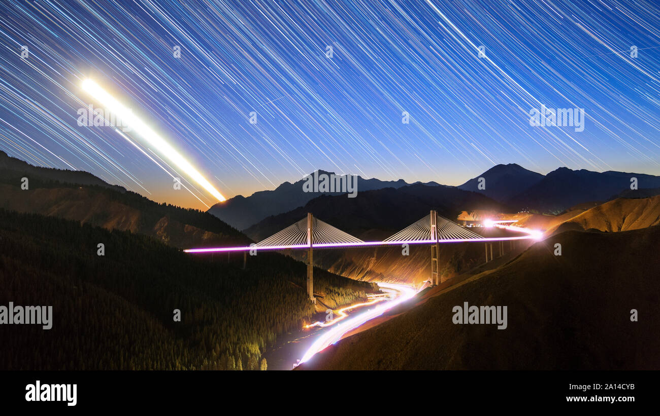 Moon, star and car light trails as they set above the Guozigou Bridge in Xinjiang, Northwest China. Stock Photo