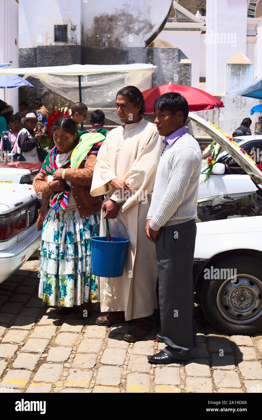 COPACABANA, BOLIVIA - OCTOBER 20, 2014: Unidentified priest with owners of a car posing for a photograph at the blessing of vehicles in Copacabana Stock Photo