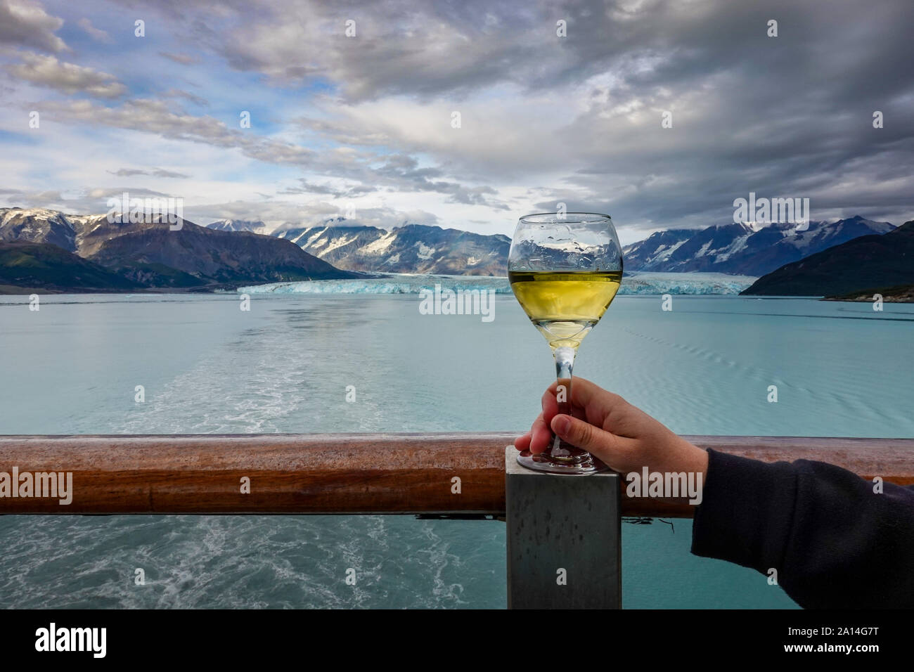 A woman drinking a glass of wine while their cruise ship is sailing away from the Hubbard Glacier. Stock Photo
