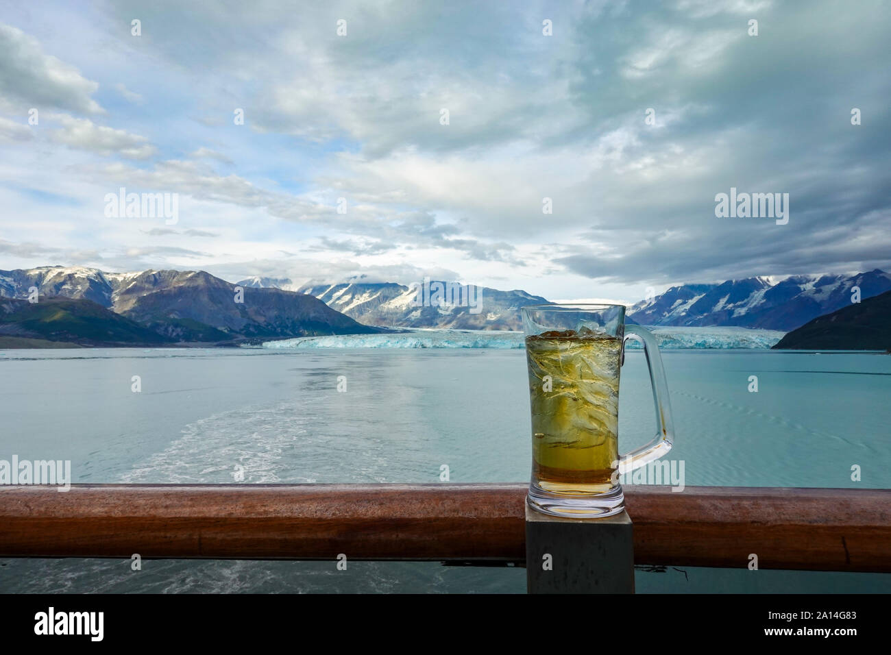 A glass of beer or beverage on the railing of a cruise ship while the ship is sailing away from the Hubbard Glacier. Stock Photo