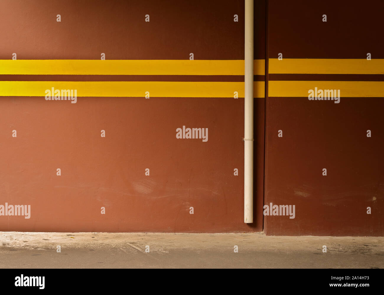 Brown wall in parking area painted with yellow stripes, which is the most visible color from distance. This can reduce damages cause by car impact Stock Photo