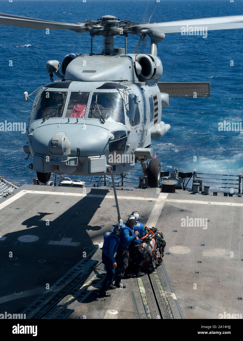 Sailors hook a cargo cable to an SH-60B Seahawk helicopter. Stock Photo