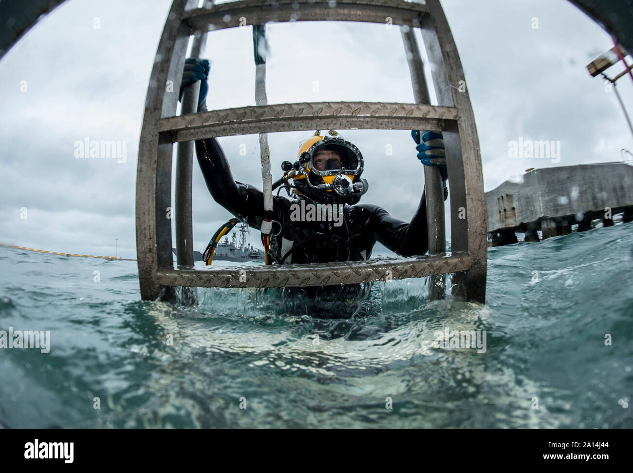 Diver ascends a ladder after completing a surface supplied dive. Stock Photo