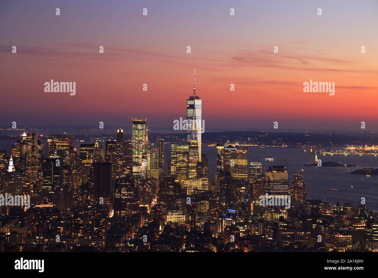 Aerial view of New York City, Lower Manhattan skyline illuminated at sunset including One World Trade Center and Liberty Island, USA Stock Photo