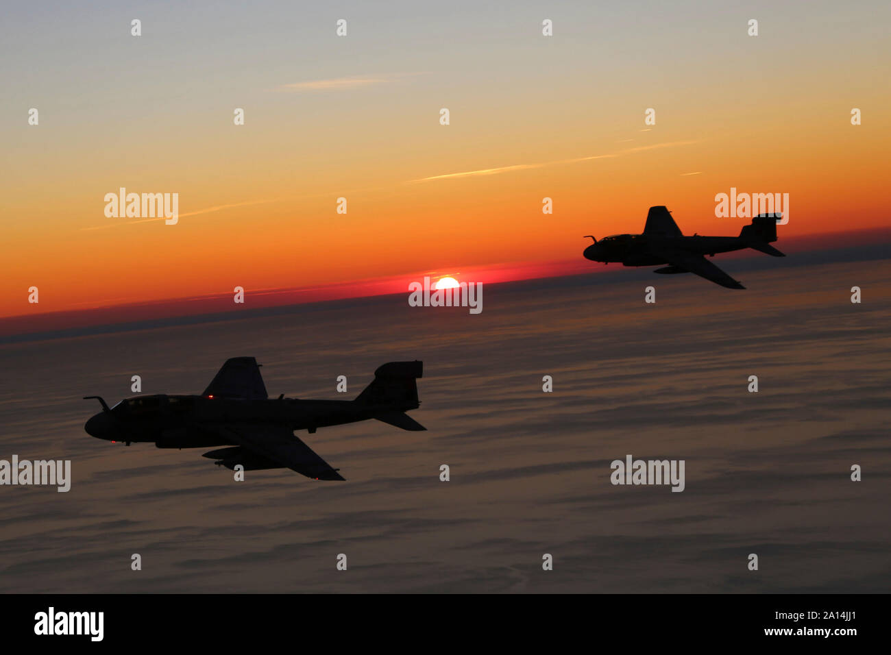Two EA-6B Prowlers are silhouetted by a setting sun. Stock Photo