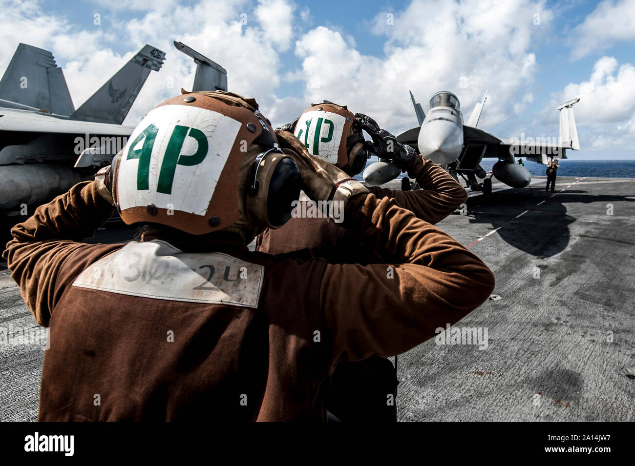 Sailors signal a pilot to test the vertical stabilizers of an F/A-18E Super Hornet. Stock Photo