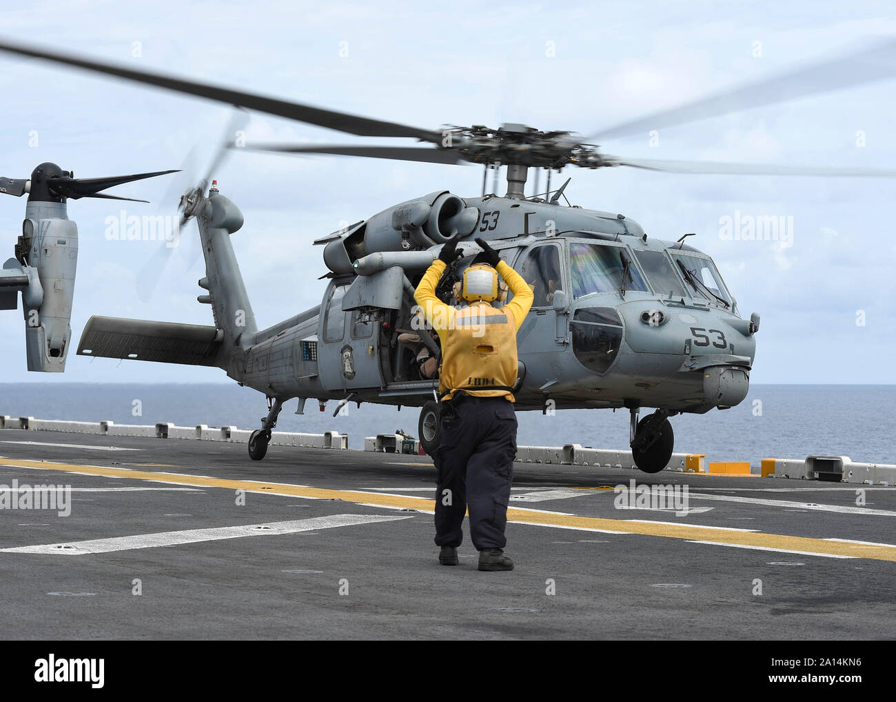 Aviation Boatswainâ€™s Mate signals an MH-60S Sea Hawk to take off from USS Boxer. Stock Photo