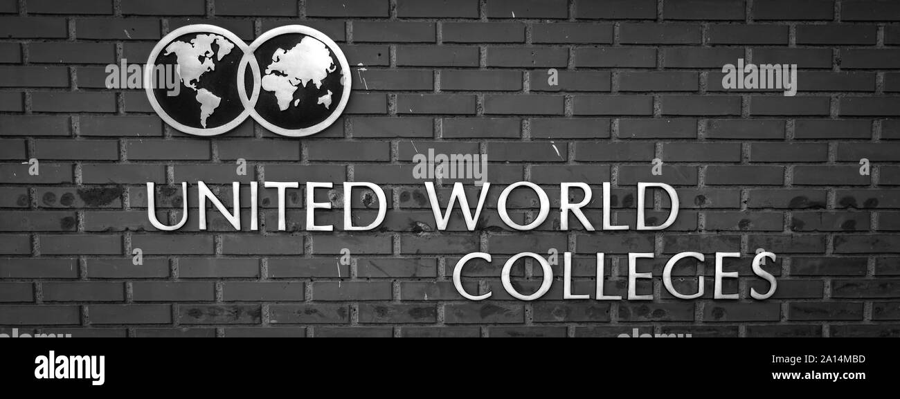 The Logo and name of the United World Colleges on the background of a grey brick wall Stock Photo