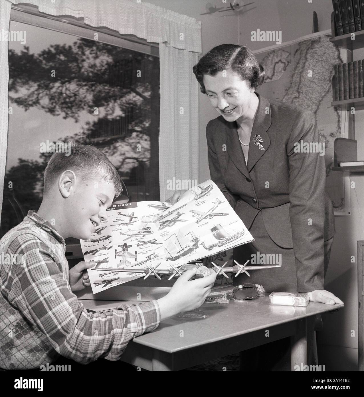 Hobby in the 1950s. A boy is sitting at a table with a plastic model of an American bomb aircraft B29. It's made by the American manufacturer of plastic models Aurora Plastics coporation. The company specialized in plane models and had it's most success with them in the 1950s and 1960s. At this time, building models of planes and cars was a very popular hobby. Sweden 1956 ref 3091 Stock Photo