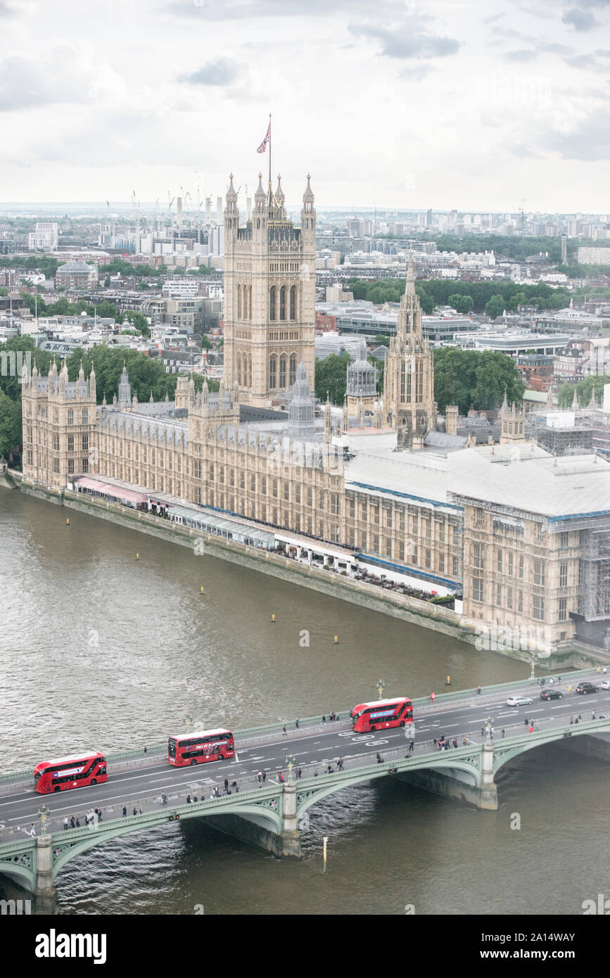 Aerial view of British Parliament (seen from London Eye), and three red Double-Decker buses crossing Westminster Bridge, over the River Thames.. Stock Photo