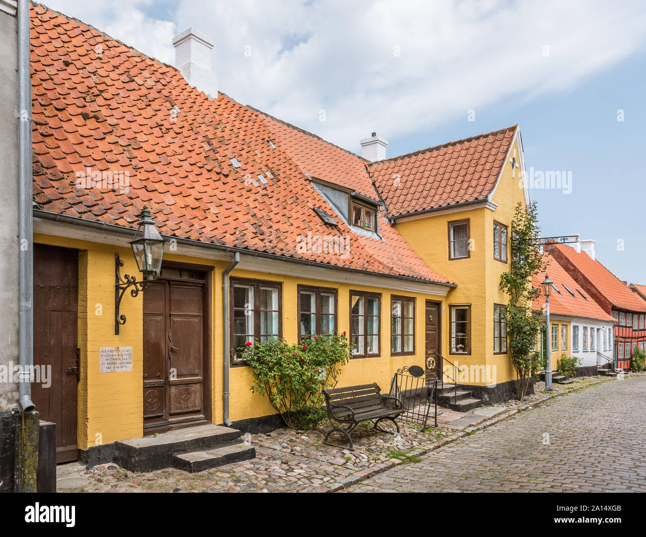 An old idyllic house with red roses in a cobbled street, island of Aero, Denmark, July 13, 2019 Stock Photo