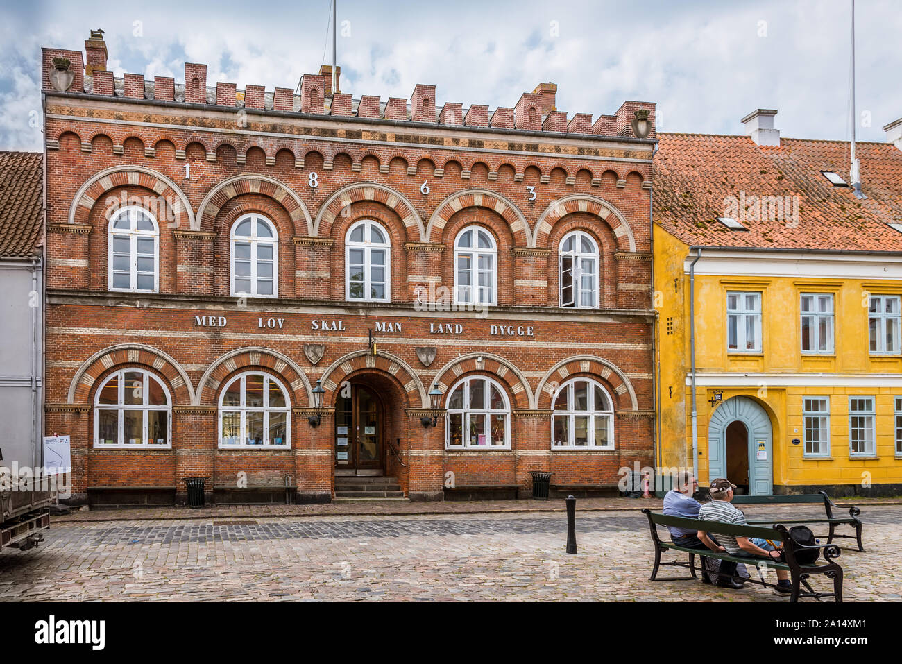 Two men sitting on a bench in front of the townhall in Ærøskøbing, Denmark, July 13, 2019 Stock Photo