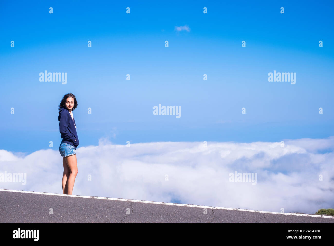 Dreaming and  freedom concept with beautiful tall standing young woman with closed eyes and clouds and blue sky in background Stock Photo