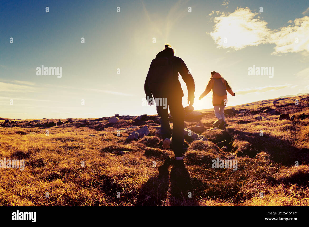 Silhouettes of two hikers walks in sunset light. Trekking concept Stock Photo