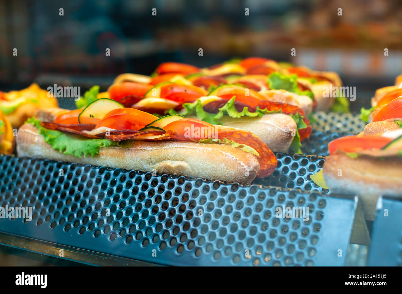Sandwich on shelf in bar. Showcase light. Fast food with bread meat and vegetables. Stock Photo