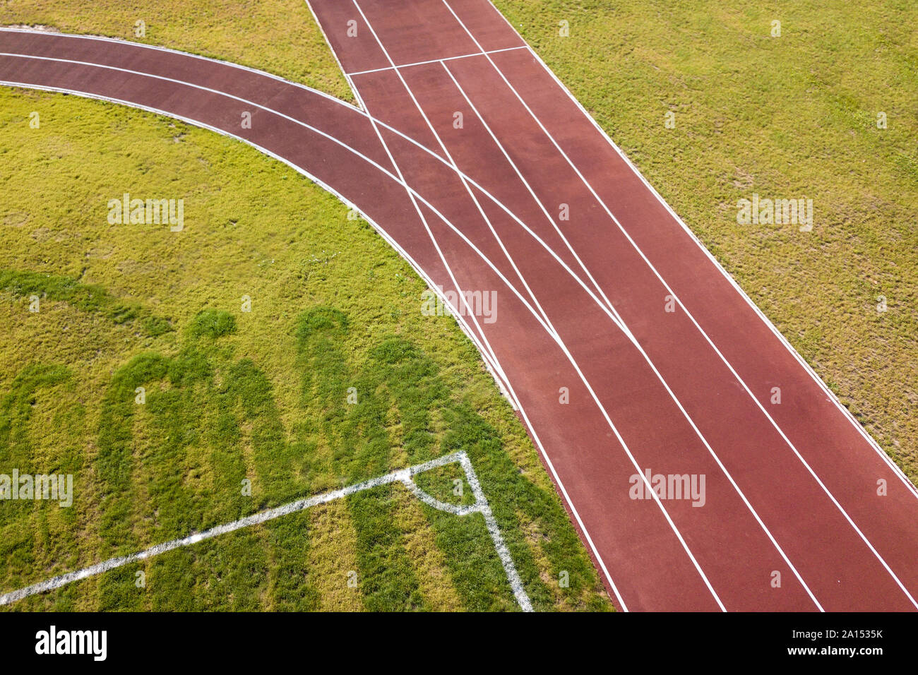 Top view of red running tracks and green grass lawn. Infrastructure for