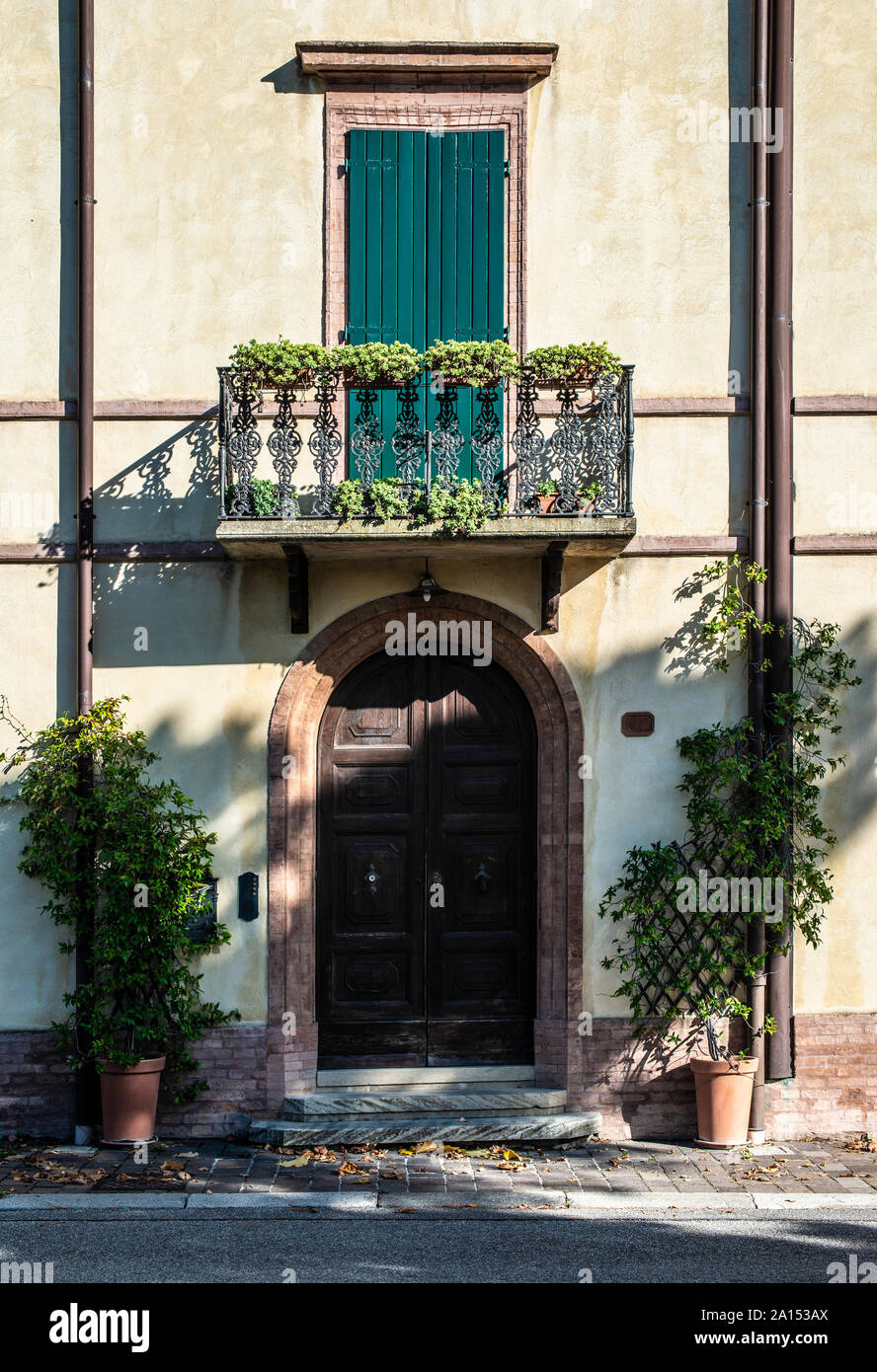 Italian style house facade. Door and terrace with flowers. Sunlight on ...
