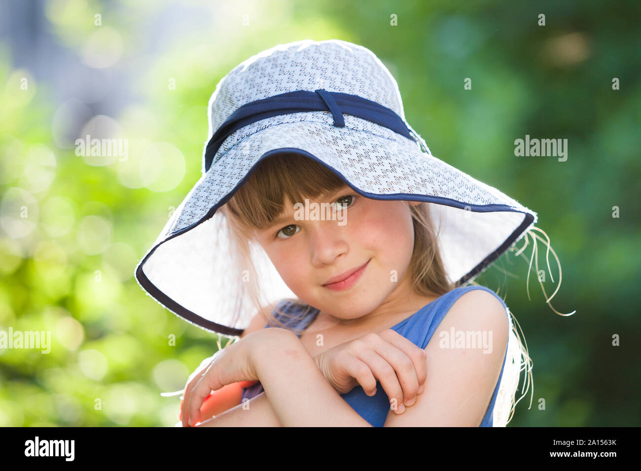 Close-up portrait of happy smiling little girl in a big hat. Child ...