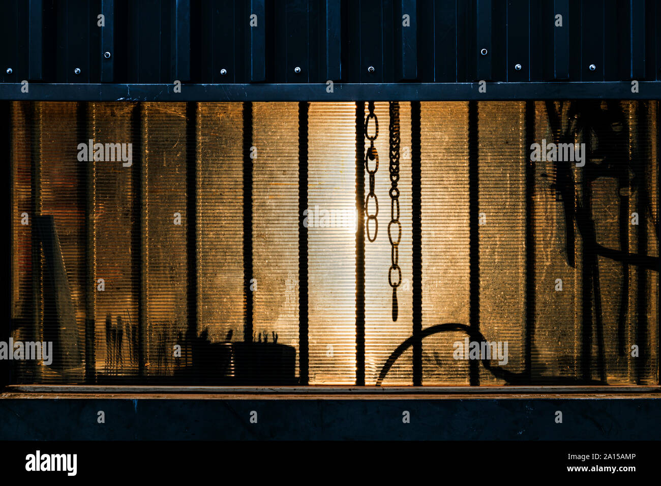 Chain hanging in the window of a steel clad building. Stock Photo