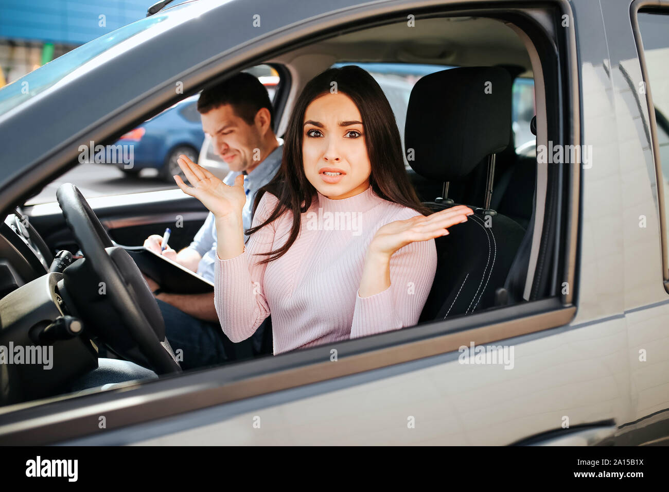 Male auto instructor takes exam in young woman. She sit on driver's ...