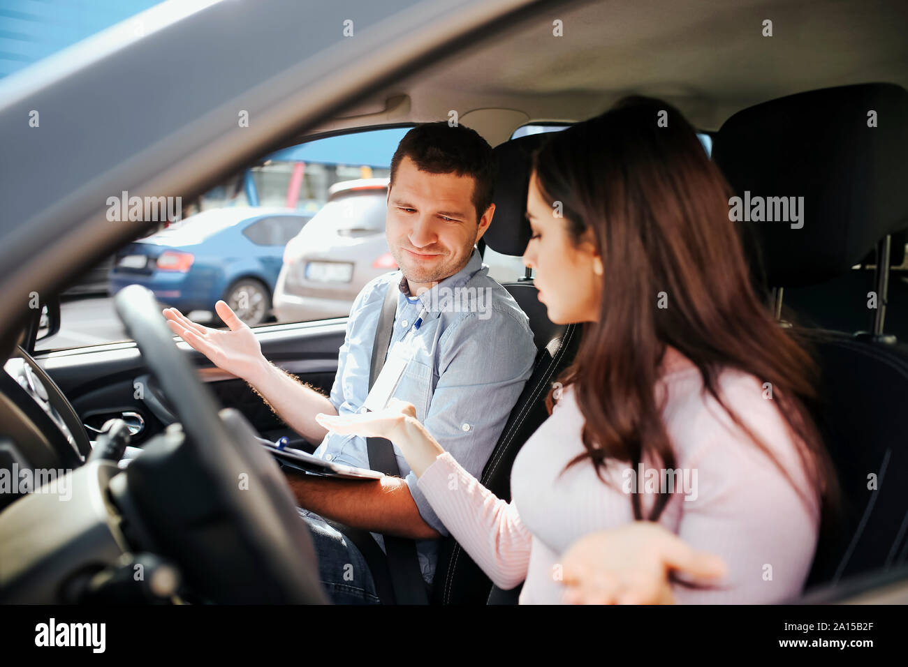 Male auto instructor takes exam in young woman. Conflict in car. People ...
