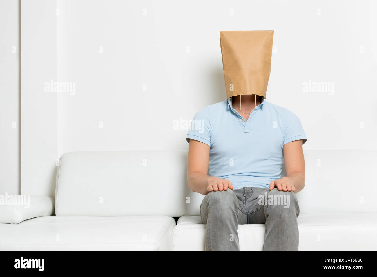 Anonymous inexpressive man with head hidden in a paper bag. Stock Photo