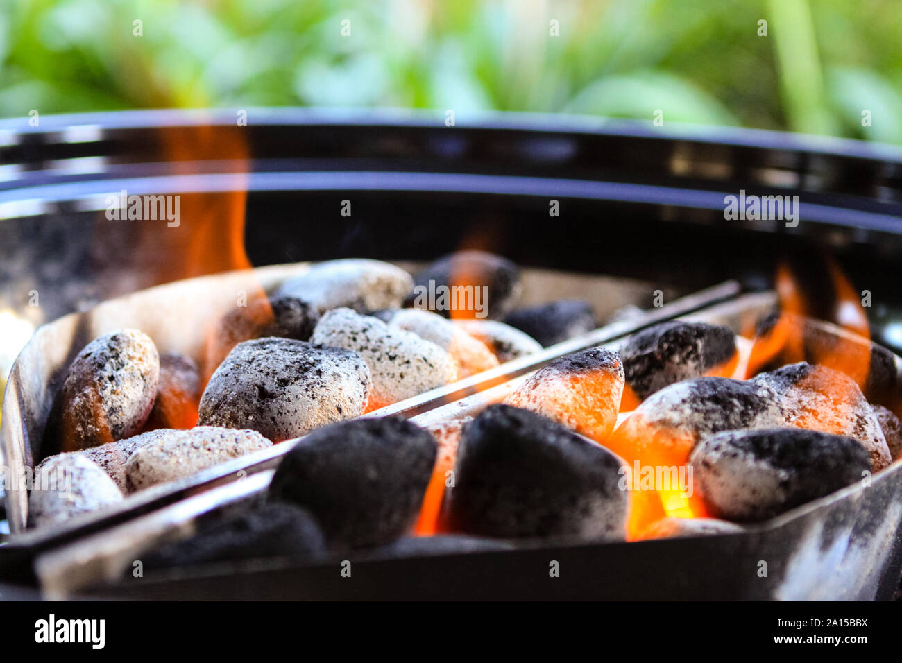 BBQ grill kettle loaded with glowing and flaming hot charcoal briquettes, ready for food to be put in and cooked. Stock Photo