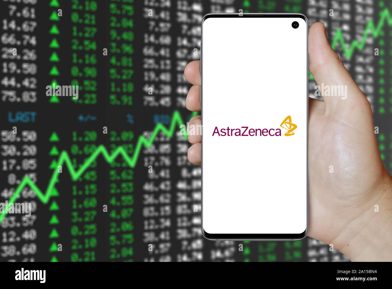 A man holds a smartphone displaying the logo of company AstraZeneca listed on OMX Stockholm. Positive stock market background. Credit: PIXDUCE Stock Photo