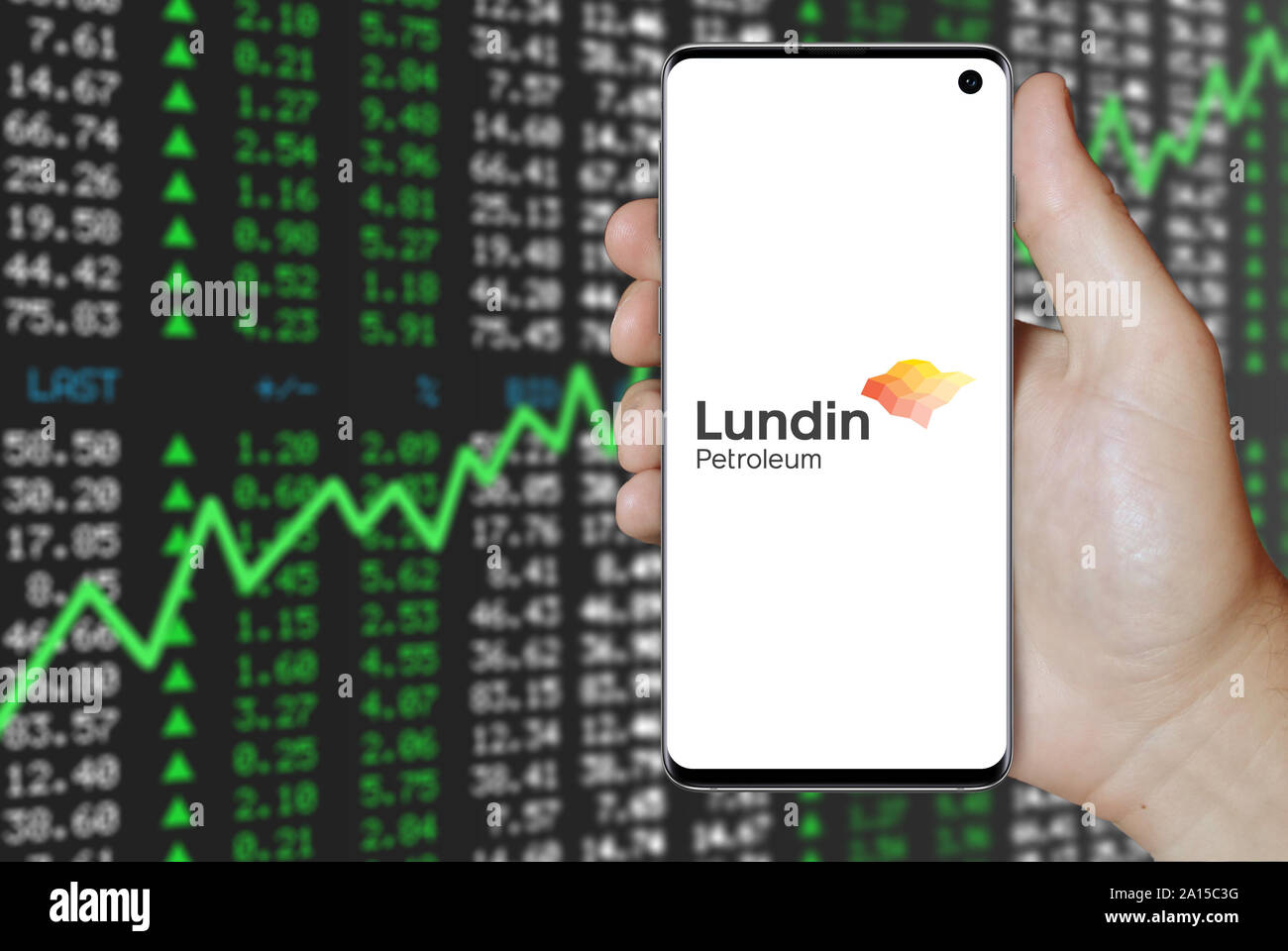 A man holds a smartphone displaying the logo of company Lundin Petroleum listed on OMX Stockholm. Positive stock market background. Credit: PIXDUCE Stock Photo