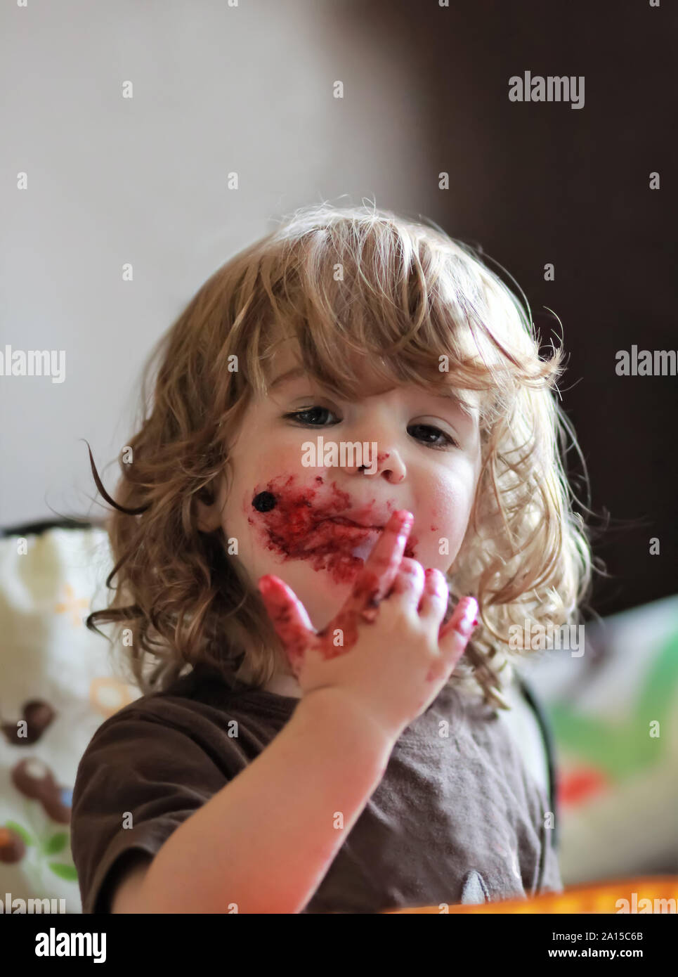 One year old baby girl eating delicious blueberry and black currant pie with her face dirty all over. Stock Photo