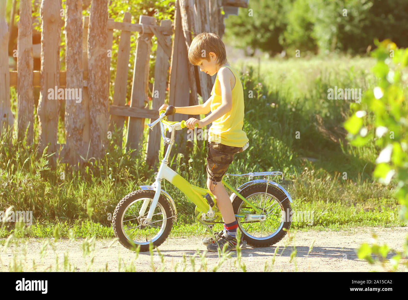 Sunlit profile portrait of six year old boy learning to ride a bicycle